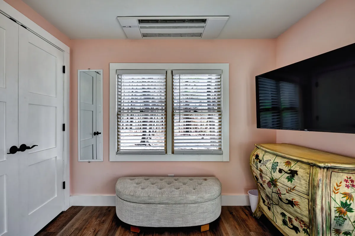 A relaxed, homey corner featuring a window for natural light, a TV for entertainment, a decorative chest, and an ottoman—providing a welcoming space for reading, socializing, or enjoying quiet moments together.