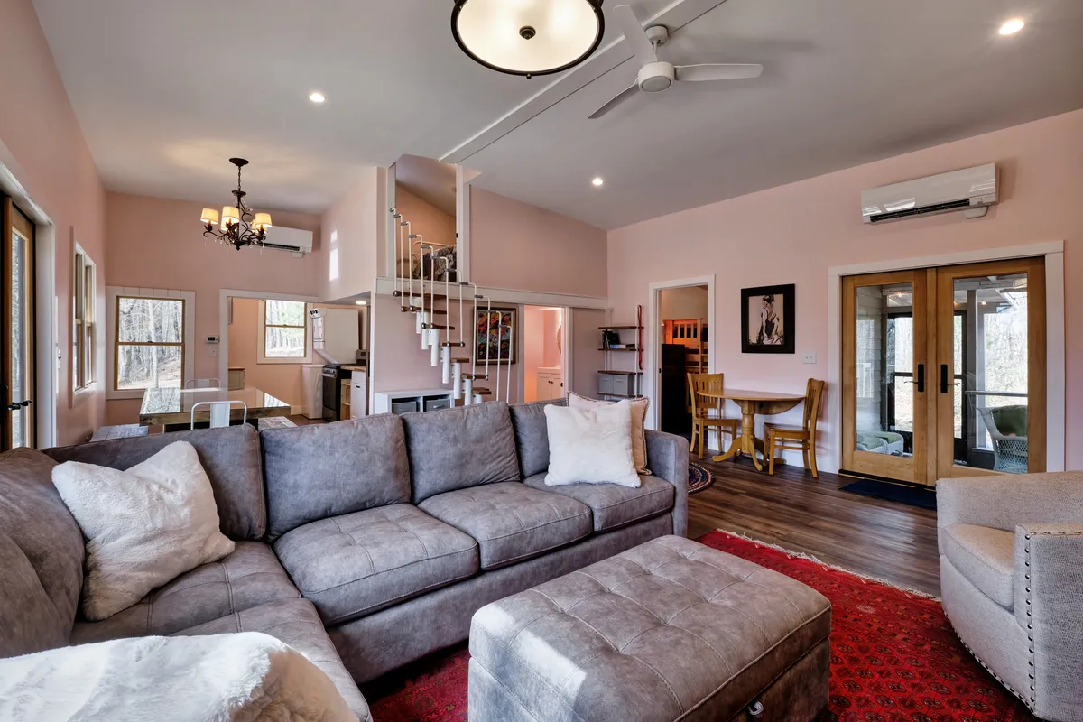 A cozy living room scene featuring a plush sofa and coffee table, with a doorway that leads outside. The soft lighting and arrangement foster a welcoming environment perfect for relaxing or entertaining guests after a day of adventure.